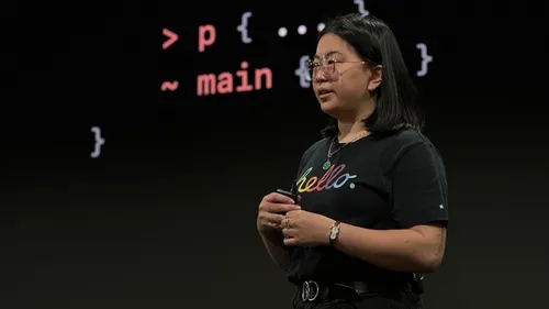 An Asian woman in a black t-shirt and glasses standing in front of a screen with a slide showing CSS selectors.