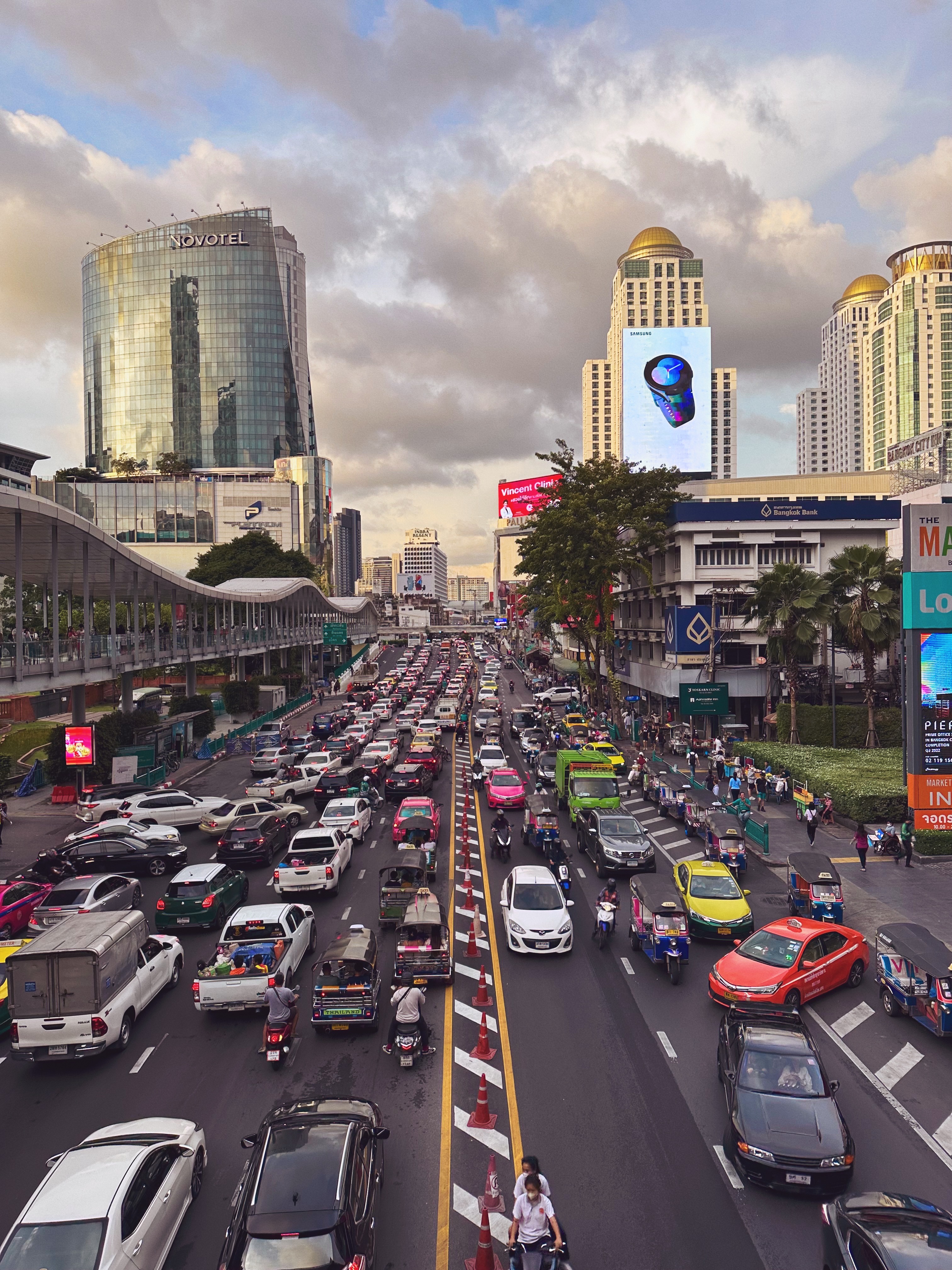 Gridlocked roads filled with cars, mopeds, and people on an afternoon in Bangkok, Thailand.
