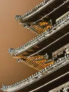 A close-up view of the intricate wooden joinery beneath Yasaka Pagoda’s roof, softly illuminated by warm light from within at night.