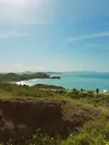 Hikers walk up Hill 88 on a sunny day, with Rodeo Beach and the coastline visible behind them in the Marin Headlands.