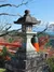 A stone lantern at Kurama-dera, framed by a vermilion wooden fence and the surrounding forested mountains.