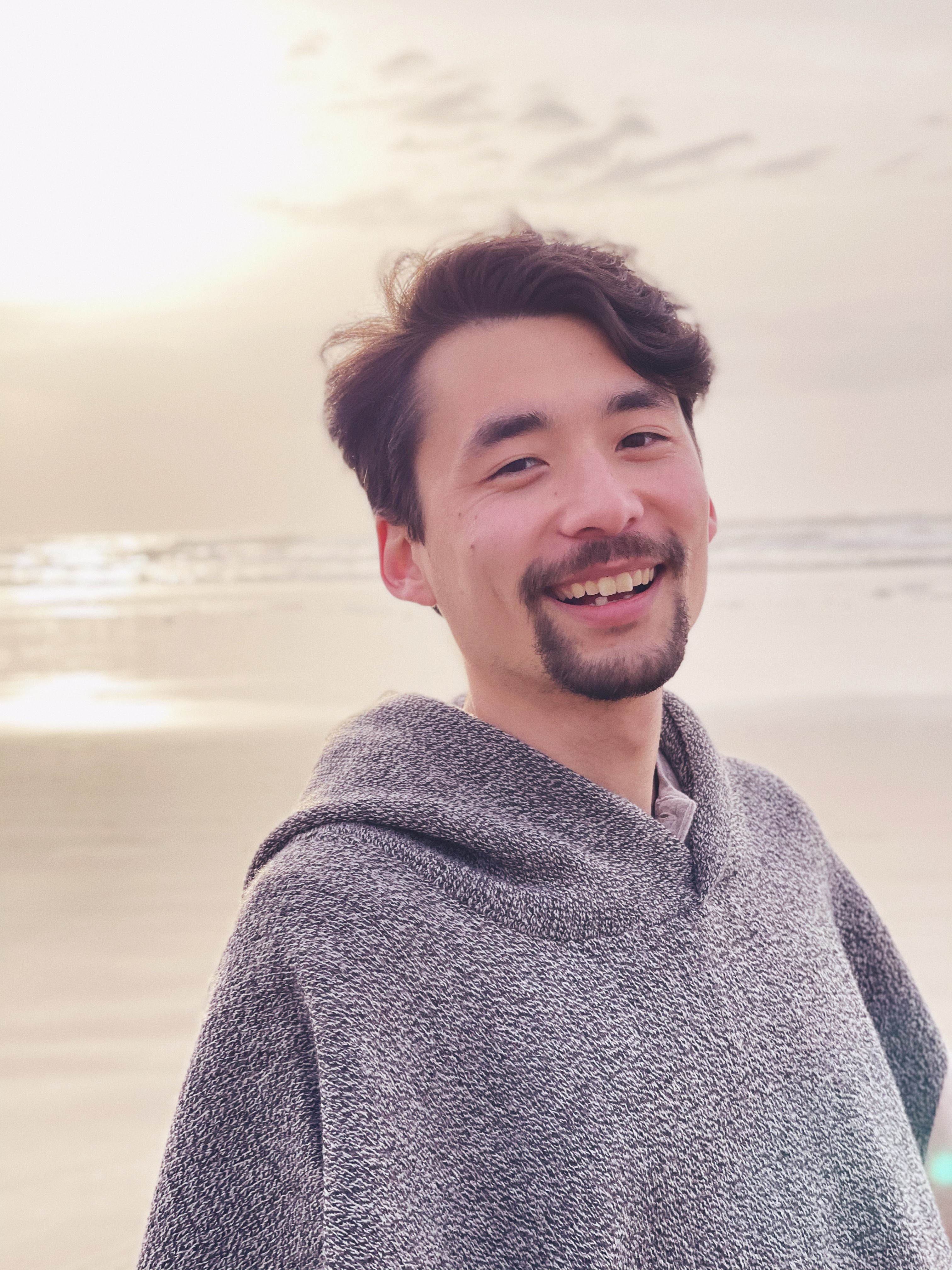 A portrait of a man in a gray poncho at a beach in Waldport, Oregon.